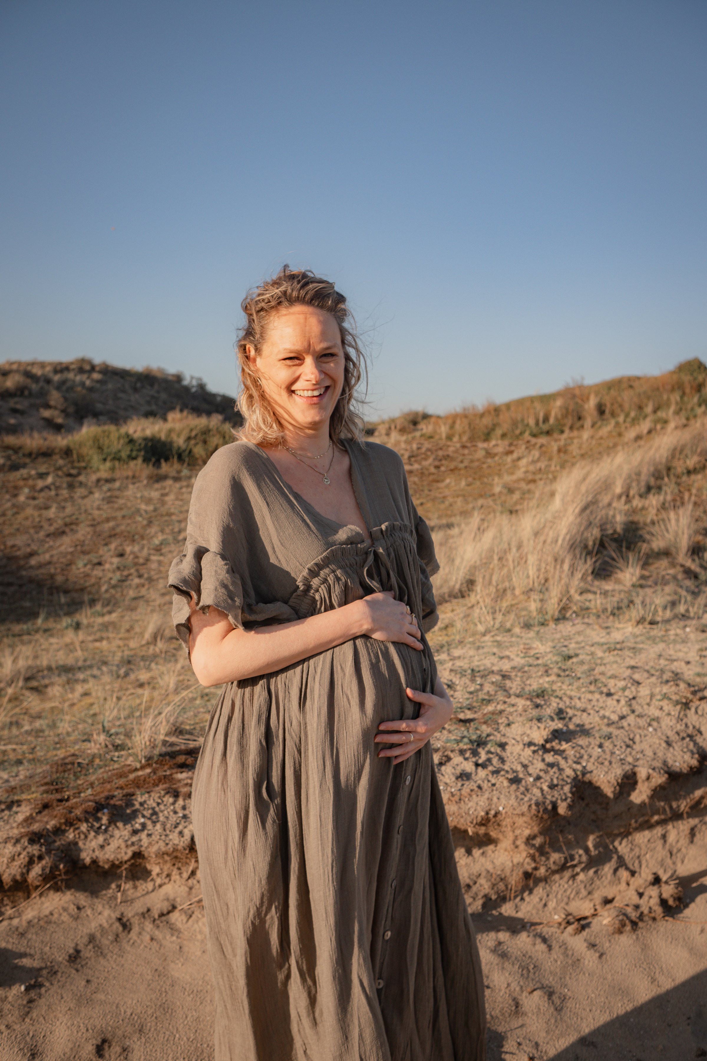 Zwangere vrouw in zachte avondzon, hand op haar buik