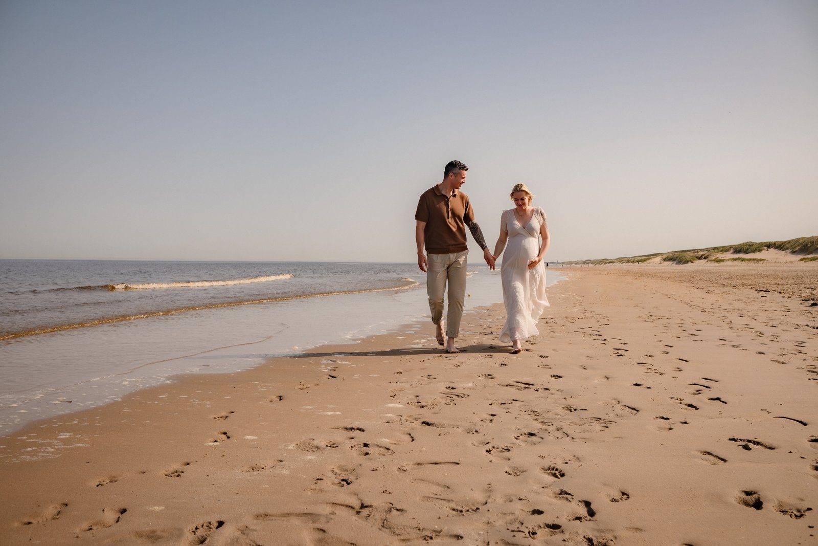 Stel wandelt hand in hand over het strand