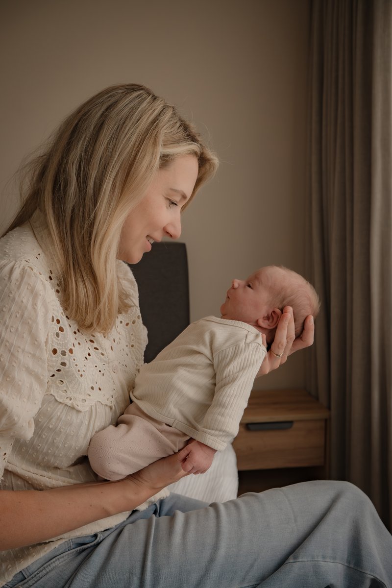 Moeder met haar newborn, intiem moment in de slaapkamer